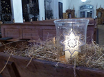 Friedenslicht - Laterne in Futterkrippe mit Stroh und Heuh in in einer Kirche